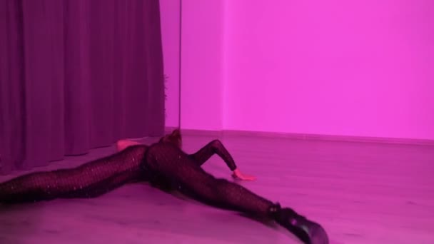 トップダンスとダンスパンツのセクシーな女性が赤いライトアップされたスタジオルームの床で踊っています 高品質のフルHd映像 — ストック動画