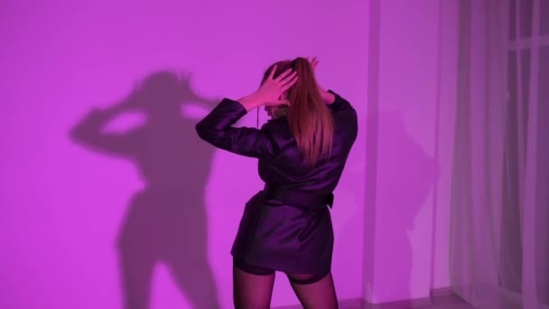 ハイヒールのセクシーな女性と革のドレスはカラフルな照明の部屋で床に踊っています 高品質のフルHd映像 — ストック動画