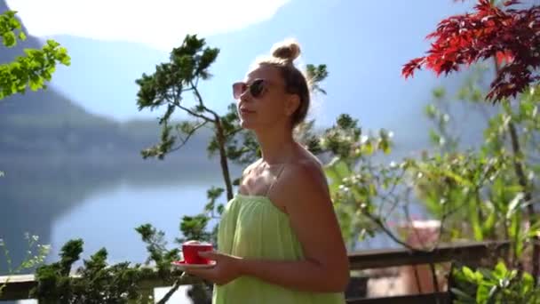 在哈尔斯塔特自然景观中 身穿绿色衣服和防晒霜的女人与咖啡呆在一起 高质量的4K镜头 — 图库视频影像