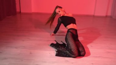 Üst dans ve dans pantolonlu baştan çıkarıcı kadın kırmızı ışıklı stüdyo odasının zemininde dans ediyor. Yüksek kaliteli FullHD görüntüler