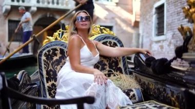 İtalya Venedik Kanalı 'nda bir gondolda oturan beyaz elbiseli muhteşem kadın. Yüksek kalite 4k görüntü
