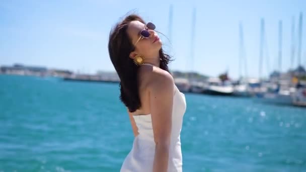 Девушка Белом Платье Солнечных Очках Причале Смотрит Камеру Наслаждается Высококачественные — стоковое видео