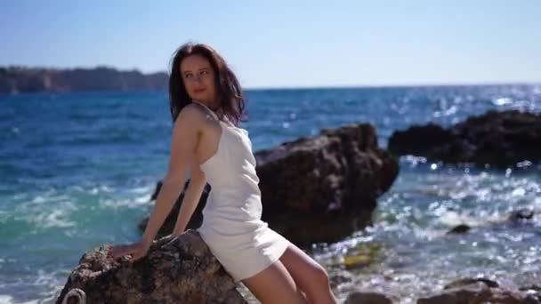 身着白衣的女孩的背影坐在岩石上 水波的背景 高质量的4K镜头 — 图库视频影像