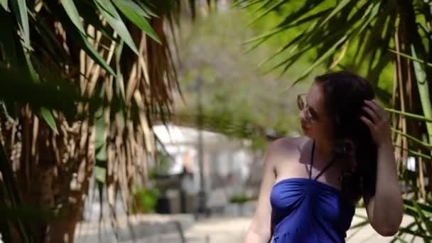 Дівчина Блакитній Сукні Сонцезахисних Окулярах Прогулюється Долоні Яскравий Сонячний День — стокове відео
