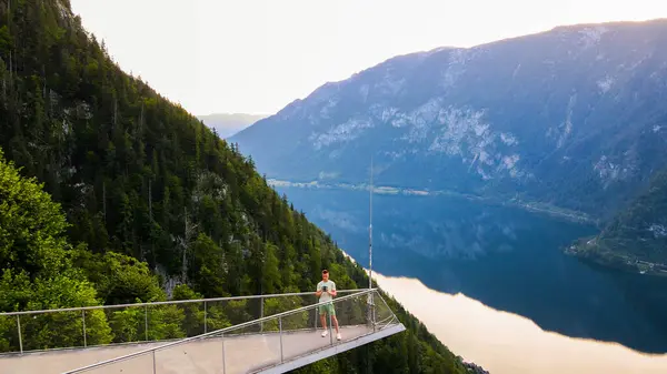 Hallstatt Gölü 'nü ve dağları gören drone kontrolörüyle izleme platformunda duran genç adam. Yüksek kalite fotoğraf