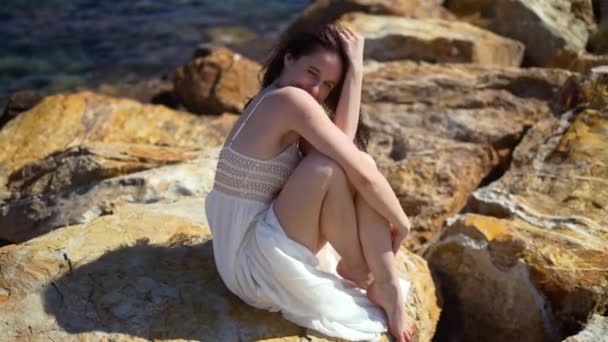 Menina Vestido Branco Sentado Quebra Mar Pedra Sorrindo Desfrutar Sol — Vídeo de Stock