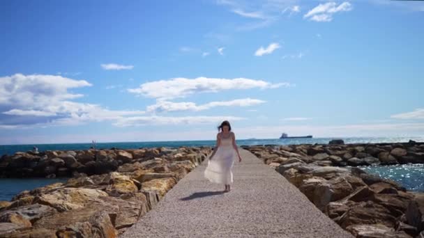 迷人的女孩穿着白衣在海滨码头或防波堤上散步 高质量的4K镜头 — 图库视频影像