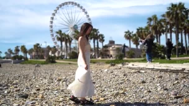 身穿白色衣服的女孩在棕榈树和摩天轮附近旋转着 享受着这一刻 高质量的4K镜头 — 图库视频影像