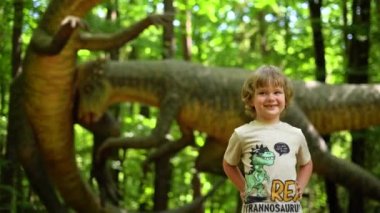 Küçük çocuk Dinopark 'ta heykel dinozor modelleri sergisi izliyor. Yüksek kalite 4k görüntü