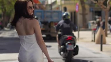Güneş gözlüklü kız İbiza caddesinde yürüyor ve kameraya bakıyor. Yüksek kalite 4k görüntü