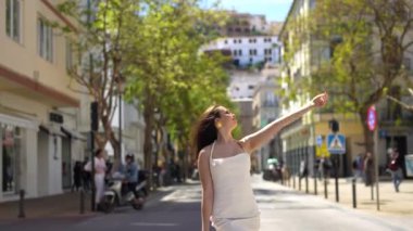 Beyaz elbiseli ve güneş gözlüklü kız İbiza caddesinde kameraya poz veriyor. Yüksek kalite 4k görüntü