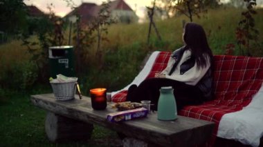 Doğada bir bankta oturmak. Güzel bir günde Park Bench 'te oturan bir kadın kahve ya da çay içer. Yüksek kalite 4k görüntü