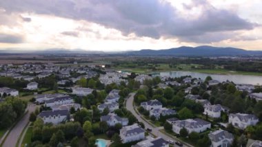 Amerikan tarzı banliyö mahallesinin panoramik insansız hava aracı görüntüsü, nehre yakın gün batımı zamanı. Yüksek kalite 4k görüntü