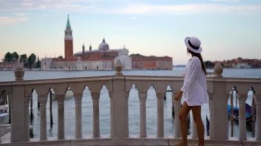 Venedik 'te Rialto köprüsünde yürüyen genç bir kadın İtalya' daki Büyük Kanal 'a bakıyor. Yüksek kalite 4k görüntü