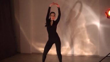 Siyah elbiseli seksi kız ve turuncu neon arka planda dans eden boğucu kız stüdyoda dans ediyor, ağır çekimde. Yüksek kaliteli FullHD görüntüler