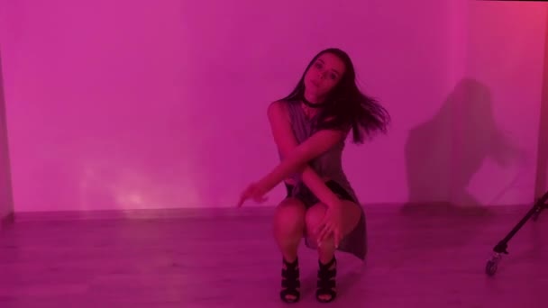ヒールの高いセクシーなブルネットの女の子がライトアップされたスタジオで床の上で踊っている 高品質のフルHd映像 — ストック動画