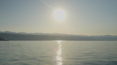 Güneşin doğuşunun klibi denizin üzerinde batıyor. Mavi gökyüzü bulutlarda parlıyor. Yüksek kalite 4k görüntü 