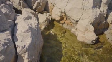 Etrafı kayalık çıkıntılarla çevrili, jeolojik oluşumlar ve dağlık arazilerle çevrili bir arazi.
