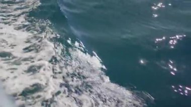 Gök mavisi gökyüzü ve hafif rüzgar dalgalarıyla çevrili geniş bir sıvı tabakasının üzerinde bir gemi oturuyor. Ufuk durgun su kütlesi boyunca uzanıyor.