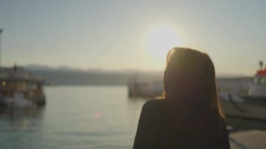 Bir kadın sakin bir gölün kenarında günbatımının tadını çıkararak anı flaşlı fotoğrafçılıkla yakalar. Güneş ufkun altına batarken gökyüzü canlı renklerle boyanır.