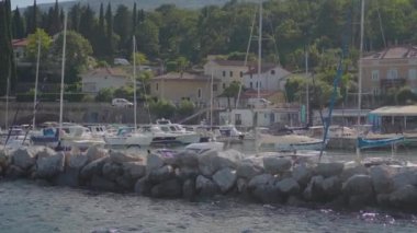 Manzaralı marina, tekneler, evler ve yeşillikler sunarak huzur ortamının manzarasını canlandırıyor.