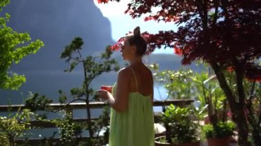 Yeşil elbiseli güzel kadın kahveyle birlikte Hallstatt Doğa Görüşü 'nde kalıyor. Yüksek kalite 4k görüntü
