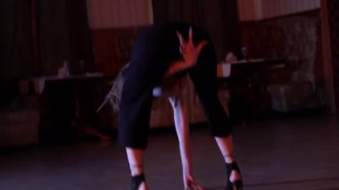 Kameraman, gri ve siyah elbiseli seksi kızın ışıklı odada dans edişinin 4K 'lık görüntüsünü çeker. Yüksek kalite 4k görüntü