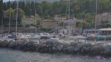 Manzaralı marina, tekneler, evler ve yeşillikler sunarak huzur ortamının manzarasını canlandırıyor.