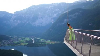 Elbiseli kadın, Alpler ve Hallstatt Gölü manzaralı izleme platformunda duruyor. Yüksek kalite 4k görüntü