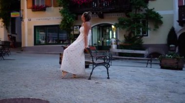 Akşam vakti Hallstatt Caddesi 'nde oturan kadın tarihi binalara bakıyor. Yüksek kalite 4k görüntü