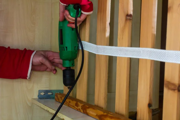 Man repairing furniture at home with a puncher