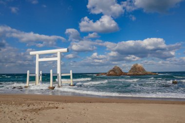 Beyaz torii kapısı plajdaki nikâh kayalarına bakıyor.