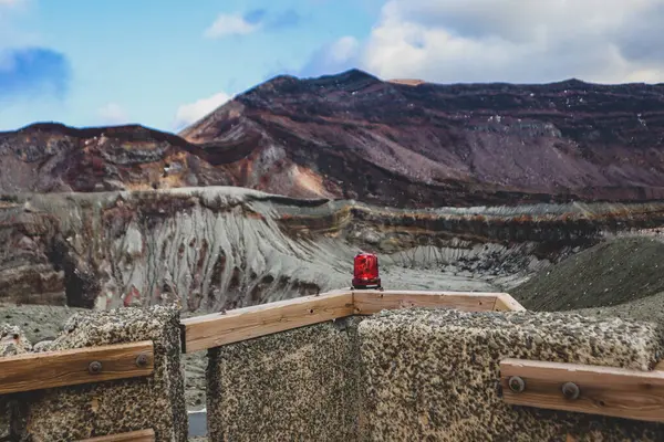 Volkanik gözlem noktasındaki kırmızı uyarı ışığı arka plandaki katmanlı volkanik araziyi çarpıcı bir şekilde gösteriyor..