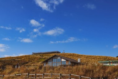 Çimenli bir tepede rahat, modern bir kulübe berrak mavi gökyüzü, huzurlu kır manzarası seyahat ve doğa kavramları için ideal..