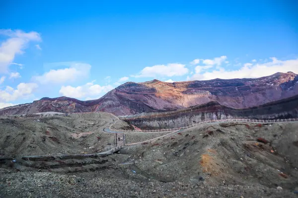 Kyushu 'da açık bir kış gökyüzü altında katmanlı kaya oluşumlarıyla Asos Dağı volkanik kraterinin manzarası.