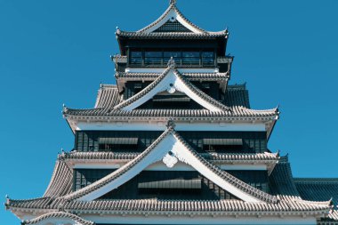 Açık mavi gökyüzüne karşı geleneksel mimarisi ile Japonya 'daki tarihi Kumamoto Kalesi.