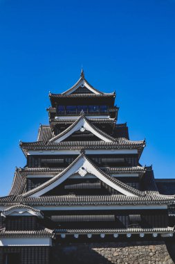 Açık mavi gökyüzüne karşı geleneksel mimarisi ile Japonya 'daki tarihi Kumamoto Kalesi.