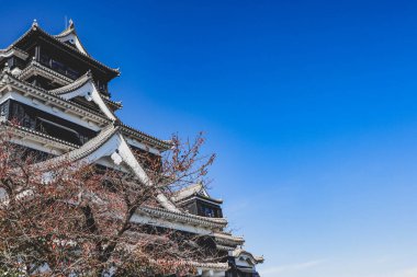 Açık mavi gökyüzüne karşı geleneksel mimarisi ile Japonya 'daki tarihi Kumamoto Kalesi.
