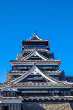 Açık mavi gökyüzüne karşı geleneksel mimarisi ile Japonya 'daki tarihi Kumamoto Kalesi.