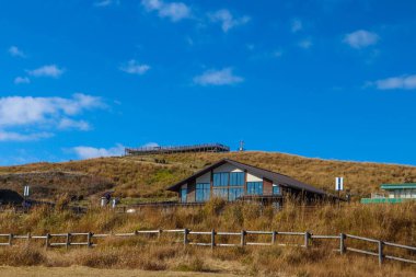 Çimenli bir tepede rahat, modern bir kulübe berrak mavi gökyüzü, huzurlu kır manzarası seyahat ve doğa kavramları için ideal..