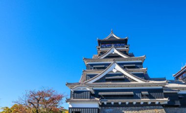 Açık mavi gökyüzüne karşı geleneksel mimarisi ile Japonya 'daki tarihi Kumamoto Kalesi.