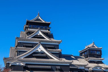 Açık mavi gökyüzüne karşı geleneksel mimarisi ile Japonya 'daki tarihi Kumamoto Kalesi.
