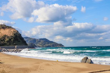 Sert Dalgalar ve Japon kıyı şeridi boyunca bulutlu gökyüzü ile Fırtınalı Okyanus Manzarası