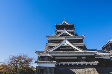 Açık mavi gökyüzüne karşı geleneksel mimarisi ile Japonya 'daki tarihi Kumamoto Kalesi.