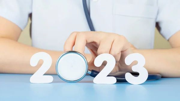 stock image Happy New Year for health care and medical concept. Doctor in white uniform holding stethoscope with number 2023 on doctor desk. Idea for new trend in medicine treatment and diagnosis.