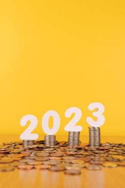 2023 Yeni Yıl Tasarruf ve Finansal Planlama. 2023 numaralı madeni para yığını altın arka planda ahşap masanın üzerinde. Ticari büyüme, yatırım, kâr ve bankacılık için yaratıcı bir fikir.
