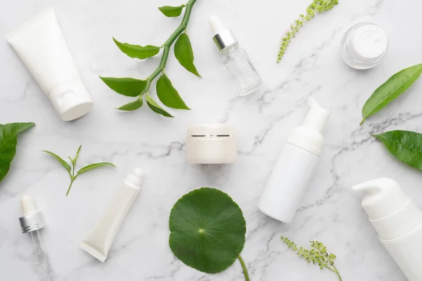 Skincare products with organic natural ingredients on marble background. Packaging of lotion, cream, serum or essence. Natural beauty cosmetology concept.