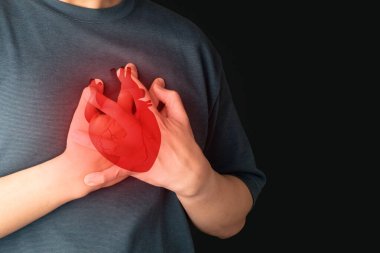 Göğüs ağrısı çeken bir adam, siyah arka planda kalp krizi geçiren bir adam. Düzensiz anjin, miyokardiyal enfarktüs, koroner arter hastalığı belirtileri. Kardiyolojik.