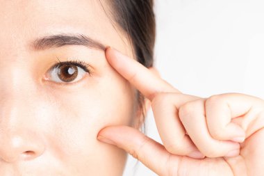 Güzel Asyalı kadın beyaz arka plan üzerinden sağlıklı gözlerine dokunuyor. Optimal göz sağlığı konsepti. Kapat..