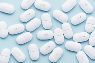 Mavi arka planda PrEP (Ön-Pozlama Profilaksi) tabletleri. HIV enfeksiyonunu önlemek için kullanılan antiviral ilaçlar.